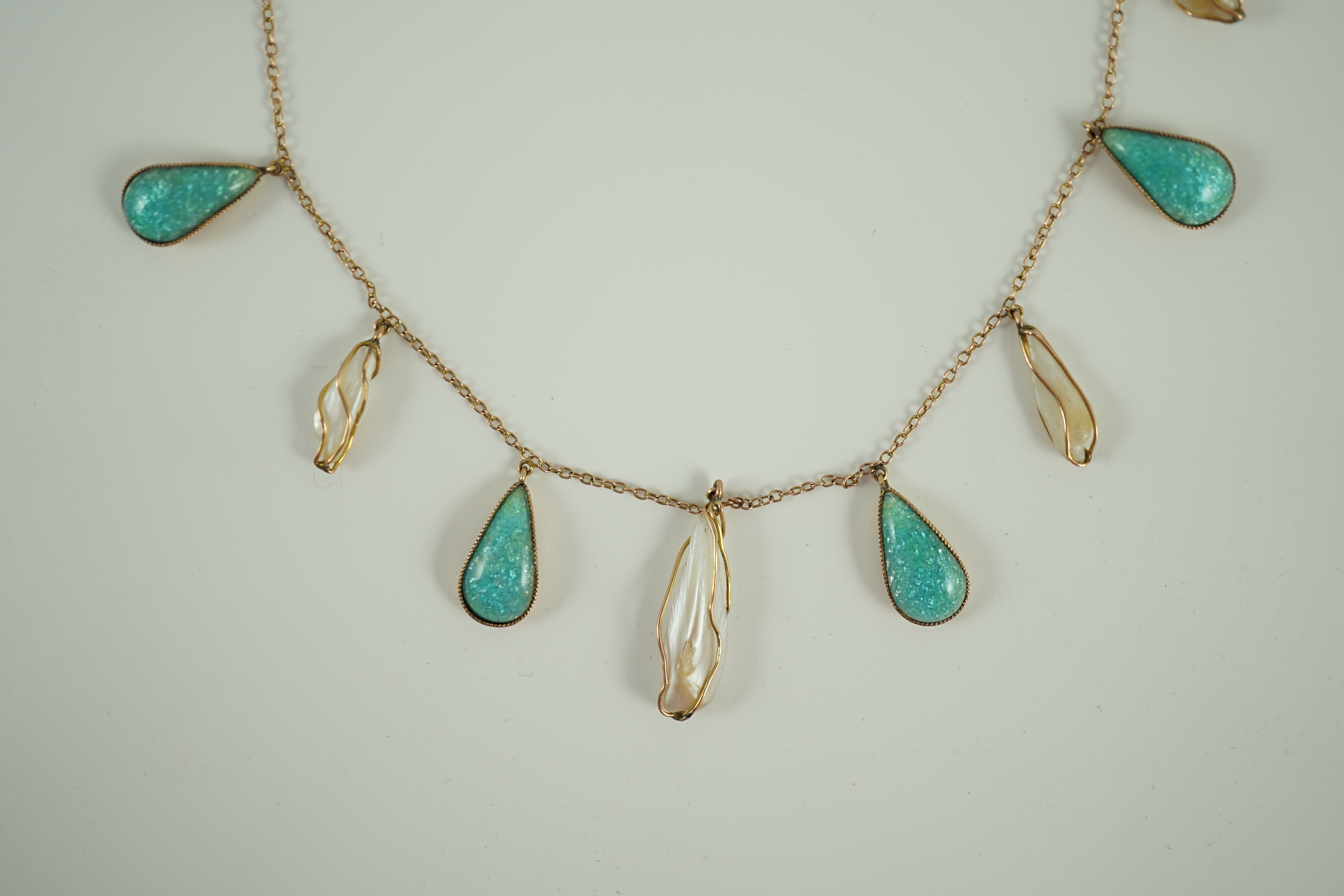 An early 20th century gold, enamel and baroque pearl set drop fringe necklace, in the manner of Liberty & Co